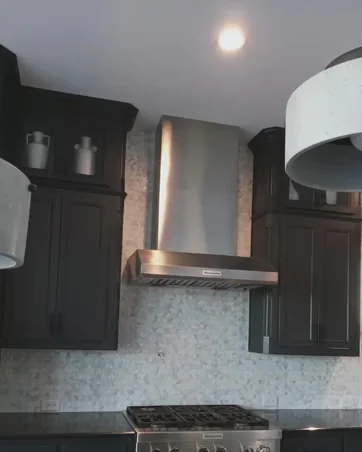 Kitchen range wall with dark cabinetry and stainless hood